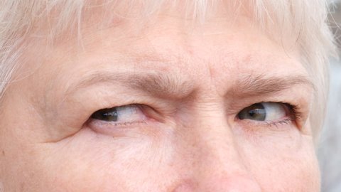 Slow motion of macro shot elderly woman. Close up of woman's eyes and changing emotions