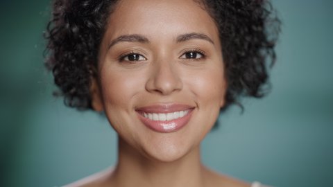 Close Up Female Beauty Portrait. Happy Multiethnic Black Brazilian Woman with Natural Healthy Skin, Curly Afro Hair Posing and Smiling. Wellness and Skincare Concept on Soft Isolated Background.