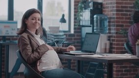 Portrait of pregnant woman working with charts on laptop. Employee expecting child and planning business project with documents and computer at startup office. Adult doing paperwork - Powered by Shutterstock - Get 15% off with code: PIKWIZARD15