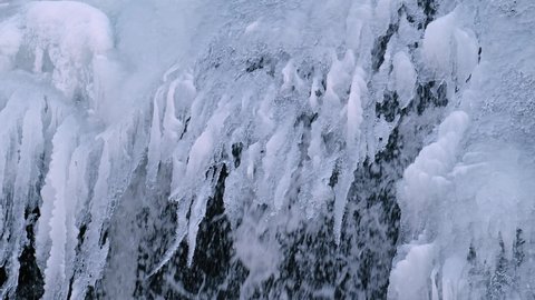 Video of frozen waterfall on river Pescherka in winter season.  Jets of water flow from under the long icicles. Siberia, Russia.