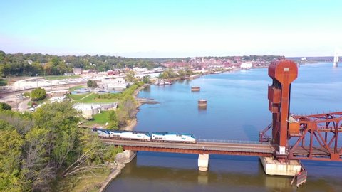 BURLINGTON, IOWA - CIRCA 2020s - Aerial of an Amtrak passenger train crosses the Mississippi River on a steel drawbridge near Burlington, Iowa.