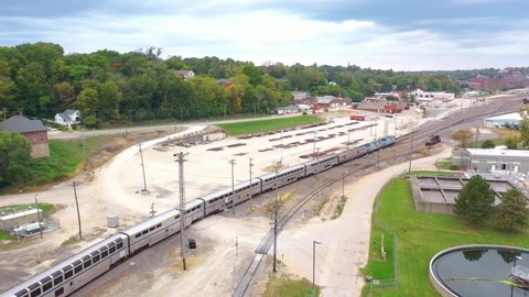 BURLINGTON, IOWA - CIRCA 2020s - Aerial of a long distance Amtrak passenger train arrives in a railyard near Burlington Iowa.