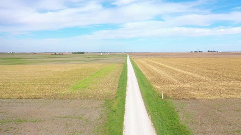 AMERICA - CIRCA 2020s - Aerial over a long straight road through Iowa, Illinois or Indiana flat farmland.