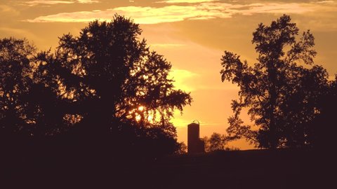 KENTUCKY - CIRCA 2020s - Establishing shot of a distant silo on a farm in rural Kentucky at sunrise or sunset.