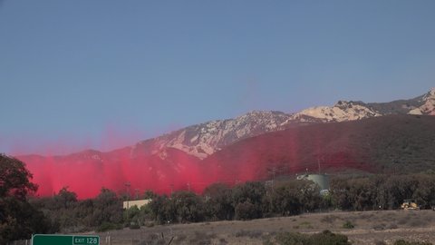 SANTA BARBARA COUNTY, CALIFORNIA - CIRCA 2021 - a large air tanker aircraft makes a dramatic drop of Phos Chek fire retardant on a mountainside.