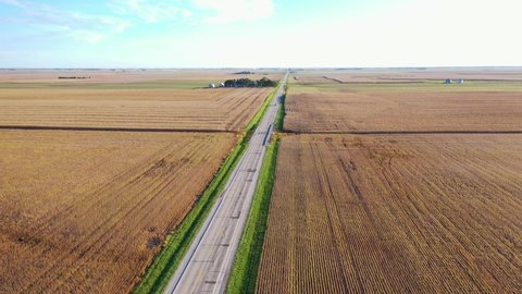 AMERICA - CIRCA 2020s - Aerial of a white van traveling on a lonely highway in the farmlands of the midwest, Illinois, Indiana, or Iowa.