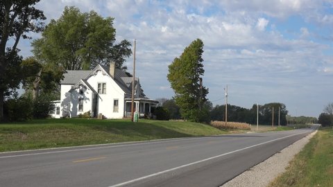 AMERICA - CIRCA 2020s - A pretty white country house from the 19th century along a pretty rural road in the Midwest, America.