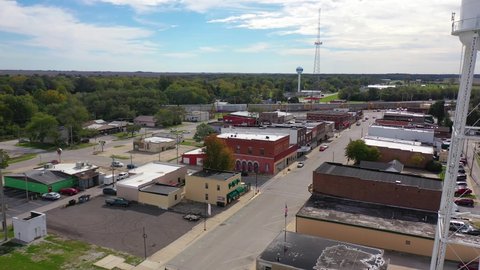 AMERICA - CIRCA 2020s - Aerial establishing shot over main street small town USA with water tower and freight train passing background.