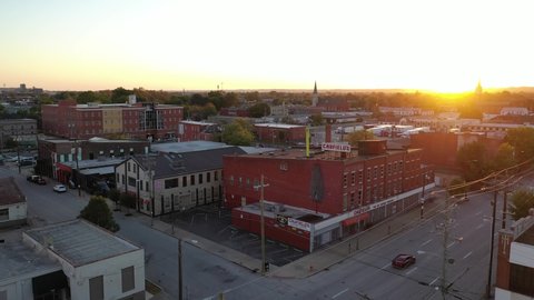 LOUISVILLE, KENTUCKY. - CIRCA 2020s - Aerial over inflatable tube man blowing on the roof of a building at sunset.