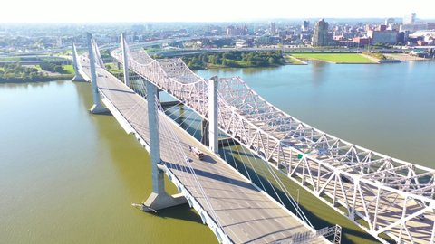 LOUISVILLE, KENTUCKY. - CIRCA 2020s - Aerial over Ohio River bridges with the Louisville, Kentucky downtown skyline distant suggests infrastructure.