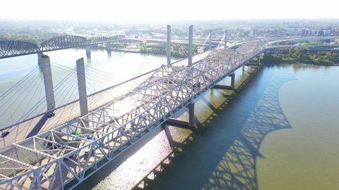LOUISVILLE, KENTUCKY. - CIRCA 2020s - Aerial over Ohio River bridges with the Louisville, Kentucky downtown skyline distant suggests infrastructure.
