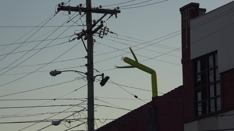 AMERICA - CIRCA 2020s - Funny or humorous shot of inflatable tube man blowing on the rooftop of a building.