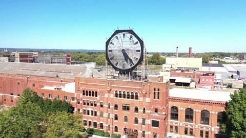 AMERICA - CIRCA 2020s - Aerial of a large old clock on the facade of an old abandoned vacant American factory near Jeffersonville, Indiana.