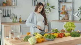 Beautiful Pregnant Woman Happily Preparing a Vegetable Salad, Organic Healthy Food, in a Cozy Home Kitchen. The Concept Of Diet, Proper Nutrition, Healthy Pregnancy and People. - Powered by Shutterstock - Get 15% off with code: PIKWIZARD15