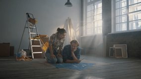 Serious couple looking blueprints of house renovation on floor. Focused young woman pointing to apartment scheme on bright background. Happy family planning home repair indoors. - Powered by Shutterstock - Get 15% off with code: PIKWIZARD15