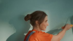 Portrait of young woman walking along wall with paint roller. Closeup smiling man moving decoration tool on surface. Happy family painting new apartment together with joy. - Powered by Shutterstock - Get 15% off with code: PIKWIZARD15