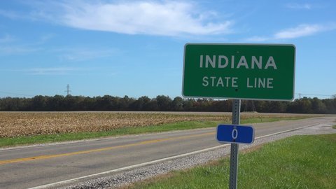 INDIANA - CIRCA 2020s - Sign indicates the Indiana State line as a truck passes on a rural road.