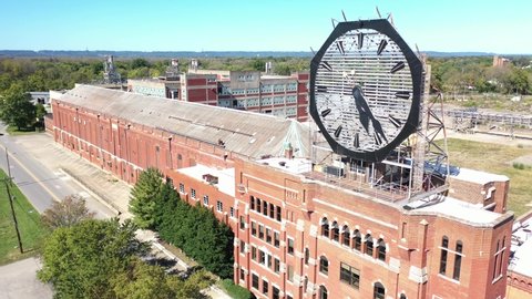 AMERICA - CIRCA 2020s - Rising aerial of a large old clock on the facade of an old abandoned vacant American factory near Jeffersonville, Indiana.