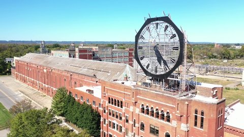 AMERICA - CIRCA 2020s - Aerial of a large old clock on the facade of an old abandoned vacant American factory near Jeffersonville, Indiana.