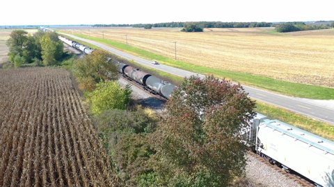 AMERICAN MIDWEST - CIRCA 2020s - Aerial of a freight train passing through cornfields in the Midwest.