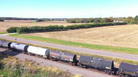 AMERICAN MIDWEST - CIRCA 2020s - Aerial of a freight train passing through cornfields in the Midwest.