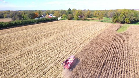 AMERICAN MIDWEST - CIRCA 2020s - Aerial of a harvester combine at work in cornfields on a rural midwest farm.