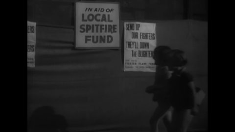 CIRCA 1940 - Children look at signs advertising a fundraiser for the RAF, and people donate by dropping coins in a tin can.