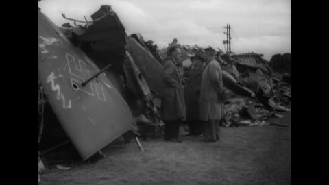 CIRCA 1940 - RAF airmen sort through the rubble of wrecked Luftwaffe planes in a junkyard.