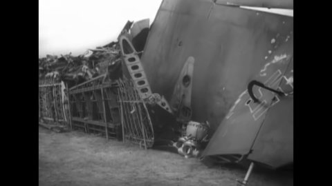 CIRCA 1940 - RAF airmen sort through the rubble of wrecked Luftwaffe planes in a junkyard.
