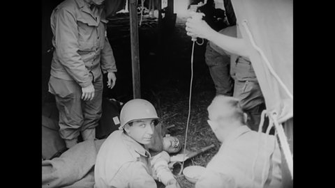 CIRCA 1940s - Nazi POWs are marched onto US Navy LCMs, while their wounded fellows are treated by US Army medics.