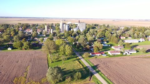 AMERICAN MIDWEST - CIRCA 2020s - Aerial establishing shot over a small farming town USA with water tower and grain silo.