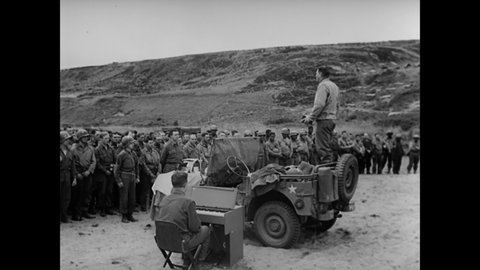 CIRCA 1944 - A chaplain holds a service for American soldiers killed on a French beach, and soldiers receive communion.