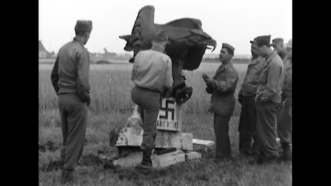 CIRCA 1945 - American soldiers wire TNT charges on the statue of a Nazi eagle and swastika.