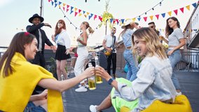 Attractive smiling young carefree women drinking beer and making selfie during summer party on terrace. Friends having fun and dancing on a rooftop party. - Powered by Shutterstock - Get 15% off with code: PIKWIZARD15
