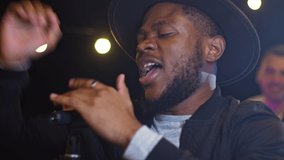 Close up of beautiful young african american man singing song on a rooftop party. Friends enjoying rooftop party music, celebrating weekend reunion gathering. - Powered by Shutterstock - Get 15% off with code: PIKWIZARD15