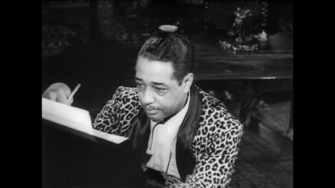 CIRCA 1940s - Duke Ellington studies his sheet music while writing a new jazz song.