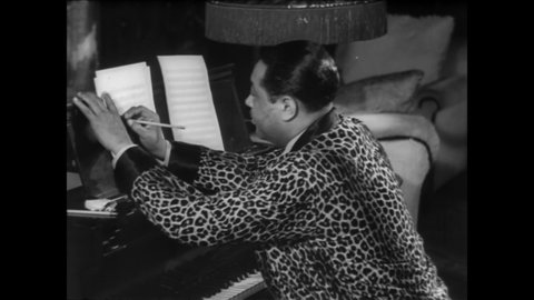 CIRCA 1940s - Duke Ellington sits and and plays at the piano while writing a new jazz composition.