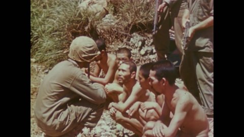 CIRCA 1945 - A US Marine interrogates Japanese POWs, and other Marines fire rockets on Okinawa.