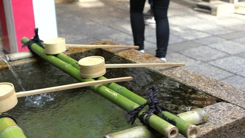 Slow Motion of purification by washing hand at the fountain of sanctuary in Kyoto. Water running from mouth of a dragon at Japan. Entrance of a Japanese shinto temple.