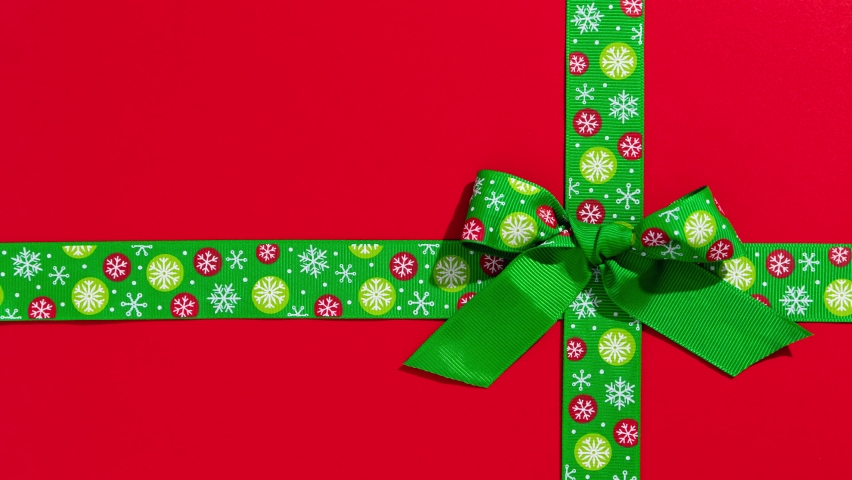 Unwrapping gift revealing a green screen - Stop Motion Animation - Green ribbon with bow on red christmas background Royalty-Free Stock Footage #1081854473