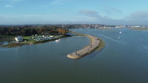 Drone aerial zoom shot of Byrhtnoth statue at the tourist town of Maldon in Essex, England. People walking on the promenade. Boats on blue water of blackwater estuary. Birds eye view