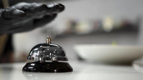 A chef in black gloves stands at the counter, presses his hand on a chrome-plated metal bell hotel restaurant. Waiter takes plate dish hall. Place insert restaurant business text into social networks - Powered by Shutterstock - Get 15% off with code: PIKWIZARD15