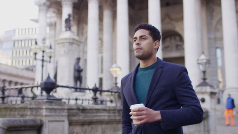 Attractive male walks through the city with a cup of coffee, in slow motion