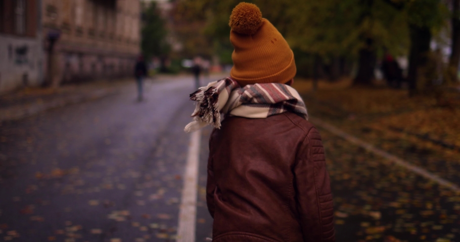 chasing a happy kid, that is running along the autumn city street