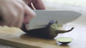 Close-up of slicing eggplant on a wooden cutting board