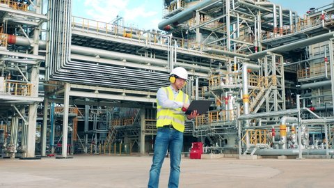 Refinery engineer is communicating via gadgets on the plant premises