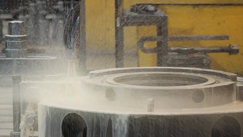 Automated Industrial Drilling Machinery Applying Coolant On Metal Turbine Component. Drill Equipment Splashing Coolant Liquid On Component. Drill Device Pours Coolant On Heavy Industry Component