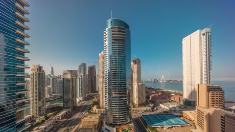 Panoramic view of the Dubai Marina and JBR area and the famous Ferris Wheel. Aerial timelapse during all day until sunset with shadows moving fast and golden sand beaches in the Persian Gulf