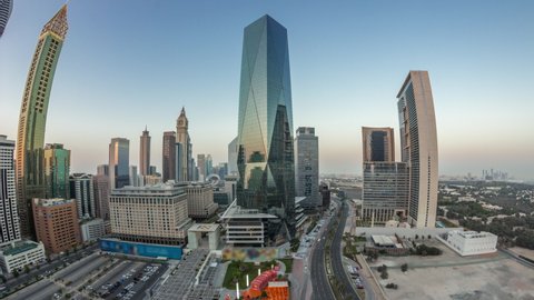 Panorama of Dubai International Financial district day to night transition timelapse. Aerial view of business office towers after sunset. Skyscrapers with hotels and shopping malls near downtown