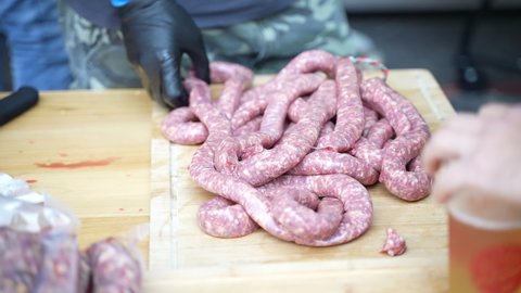 Fresh raw meat sausages on wooden board prepared for BBQ grilling on Oktoberfest party, annual Bavarian picnic party tradition with roasting bratwurst sausages and drinking refreshing homemade beer